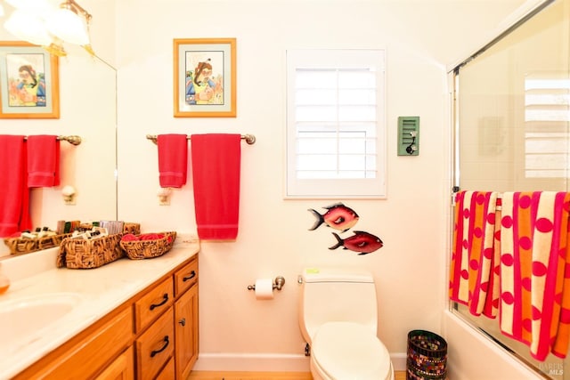 bathroom featuring vanity, baseboards, toilet, and shower / bath combination with glass door