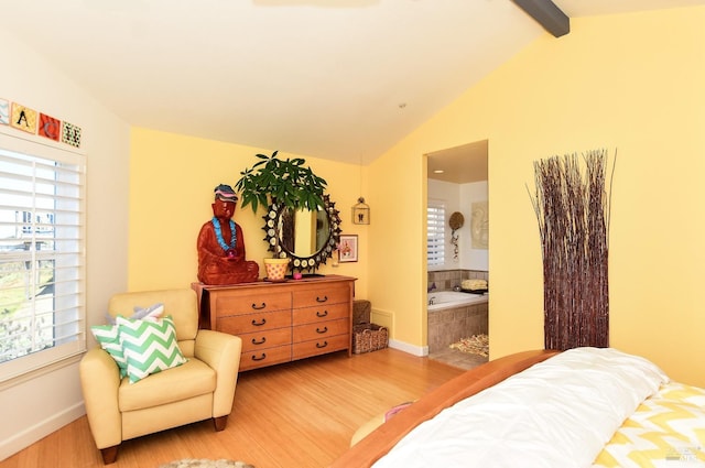 bedroom with lofted ceiling with beams, hardwood / wood-style flooring, and ensuite bath