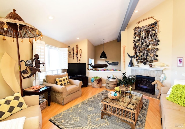 living room featuring lofted ceiling, wood-type flooring, and a tile fireplace