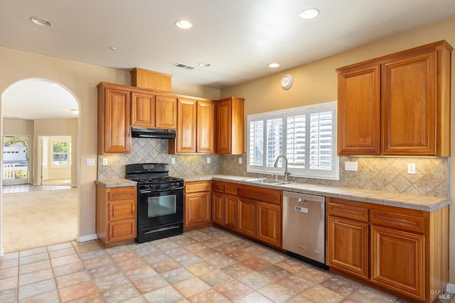 kitchen with black gas range, dishwasher, decorative backsplash, tile counters, and sink