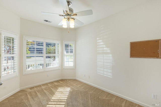 carpeted spare room featuring ceiling fan and a healthy amount of sunlight