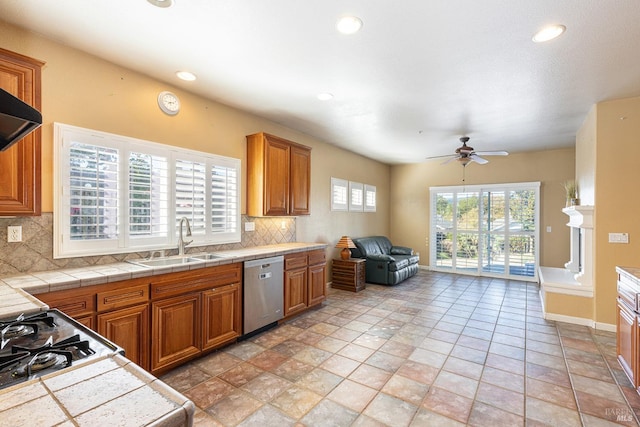 kitchen with stainless steel dishwasher, sink, decorative backsplash, and tile counters