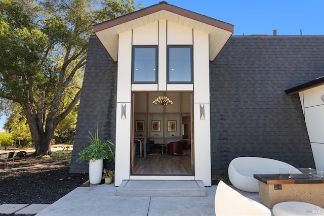 doorway to property featuring roof with shingles