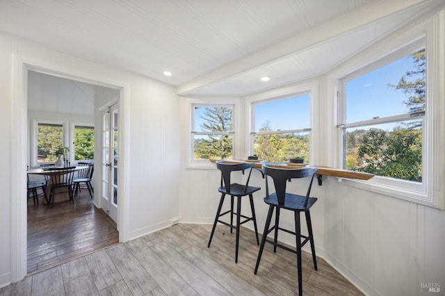 dining room featuring baseboards, light wood-style flooring, and a decorative wall