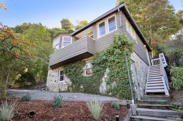 view of front of home featuring stone siding and stairs