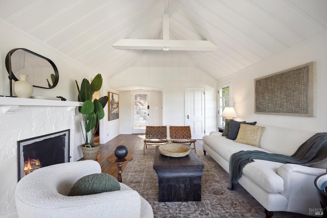 living area featuring lofted ceiling with beams, a lit fireplace, and wood finished floors