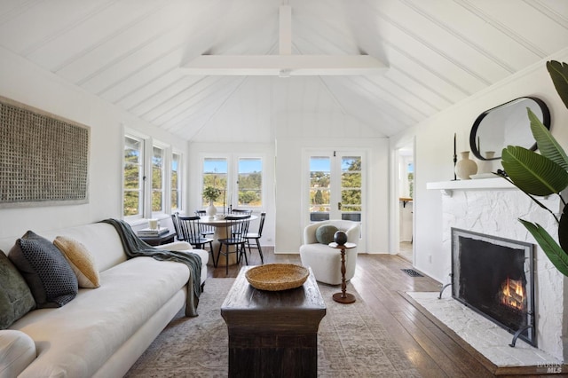 living area featuring high vaulted ceiling, a premium fireplace, wood finished floors, visible vents, and beamed ceiling