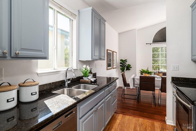 kitchen with sink, light hardwood / wood-style flooring, gray cabinetry, and dark stone counters