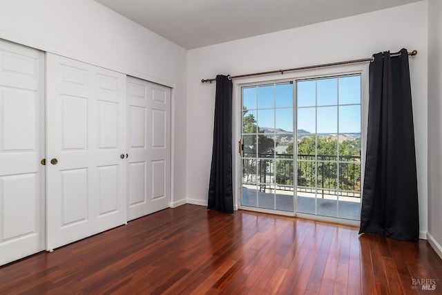 unfurnished bedroom with dark wood-type flooring, a closet, and access to outside