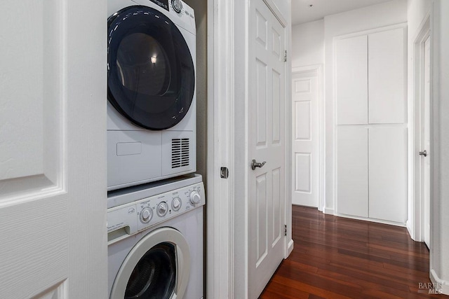 washroom featuring stacked washer and clothes dryer and dark hardwood / wood-style floors