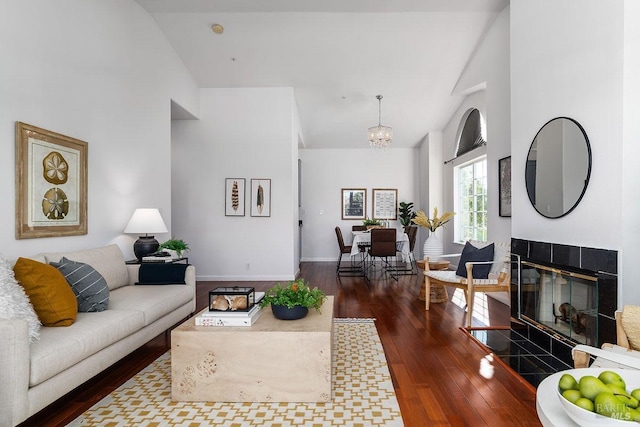 living room featuring dark wood-type flooring, a chandelier, and a fireplace