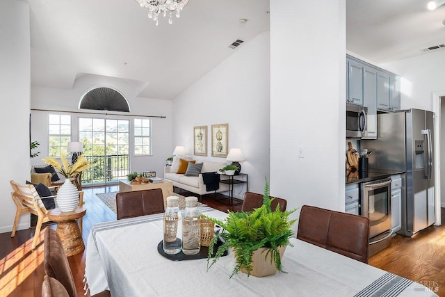 dining room featuring lofted ceiling, wood-type flooring, and an inviting chandelier