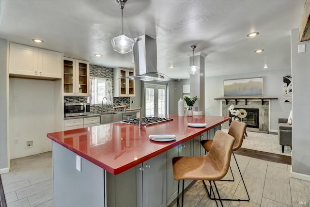 kitchen with island range hood, french doors, pendant lighting, white cabinets, and a breakfast bar