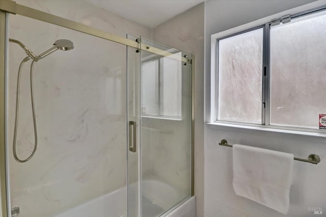 bathroom featuring a wealth of natural light and shower / bath combination with glass door