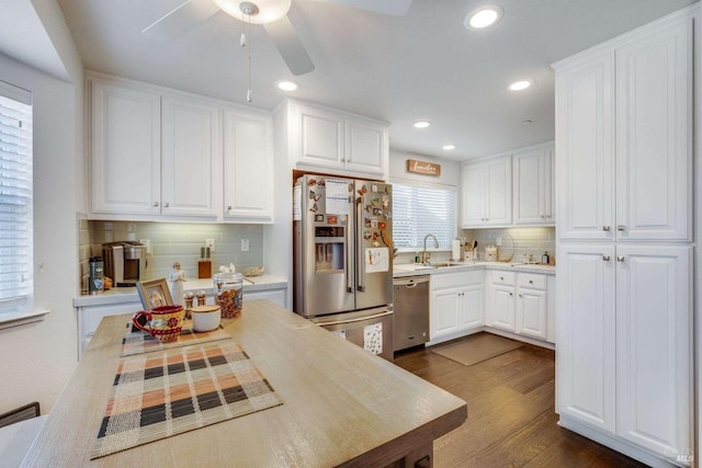 kitchen with appliances with stainless steel finishes, sink, white cabinetry, dark wood-type flooring, and decorative backsplash