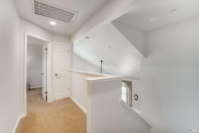 hall featuring lofted ceiling and light carpet