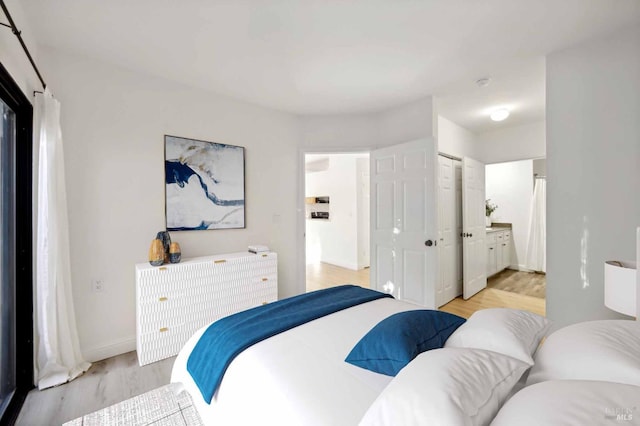 bedroom with ensuite bathroom, a closet, and light wood-type flooring