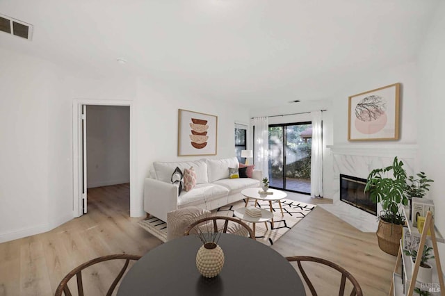 living room with light hardwood / wood-style floors and a high end fireplace