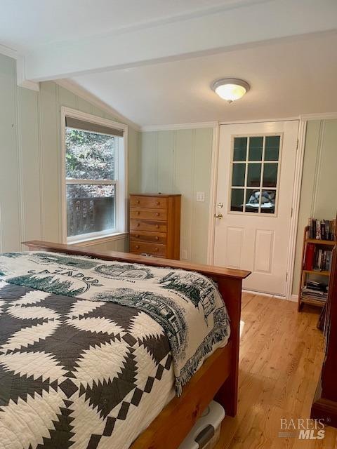 bedroom featuring light wood-type flooring and lofted ceiling with beams