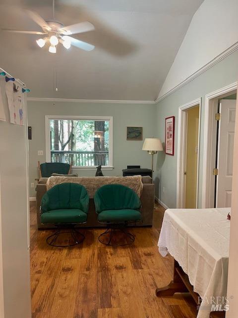 living room with hardwood / wood-style flooring, ceiling fan, and vaulted ceiling