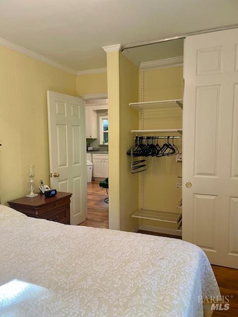 bedroom featuring ornamental molding, wood-type flooring, and a closet