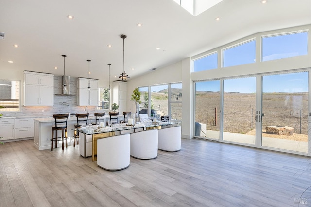 kitchen with hanging light fixtures, a breakfast bar area, white cabinetry, light hardwood / wood-style flooring, and a center island