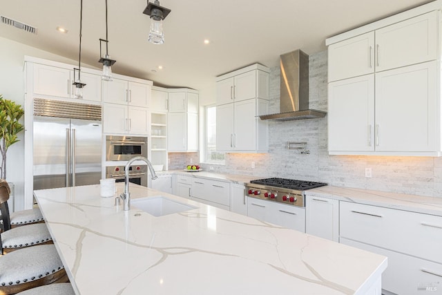 kitchen with wall chimney range hood, a breakfast bar area, appliances with stainless steel finishes, and white cabinets