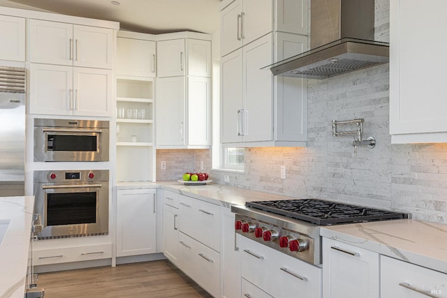 kitchen featuring white cabinetry, wall chimney range hood, and stainless steel gas cooktop