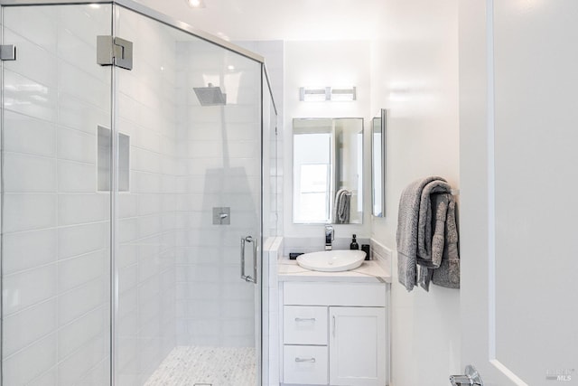 bathroom featuring a shower with door and vanity