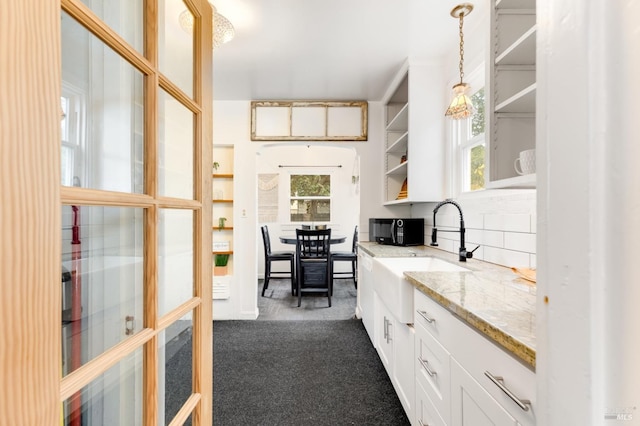 kitchen with white cabinetry, plenty of natural light, pendant lighting, and sink