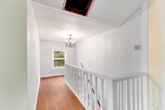 hall with wood-type flooring and a notable chandelier