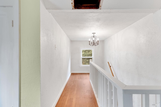 corridor with wood-type flooring and an inviting chandelier