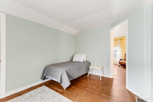 bedroom with hardwood / wood-style floors and lofted ceiling