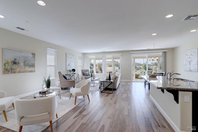 living room with light hardwood / wood-style flooring, sink, and an inviting chandelier