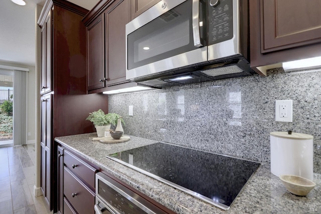 kitchen featuring dark brown cabinetry, decorative backsplash, stainless steel appliances, and light stone counters