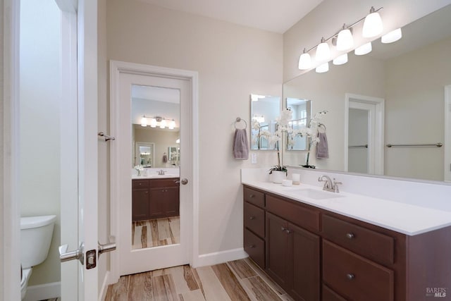 bathroom with toilet, vanity, and hardwood / wood-style floors