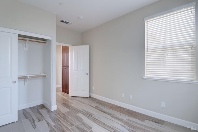 unfurnished bedroom with light wood-type flooring and a closet