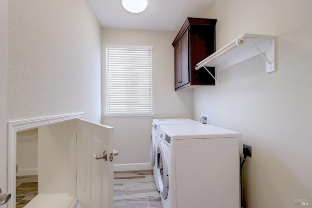 washroom with light wood-type flooring, washing machine and dryer, and cabinets