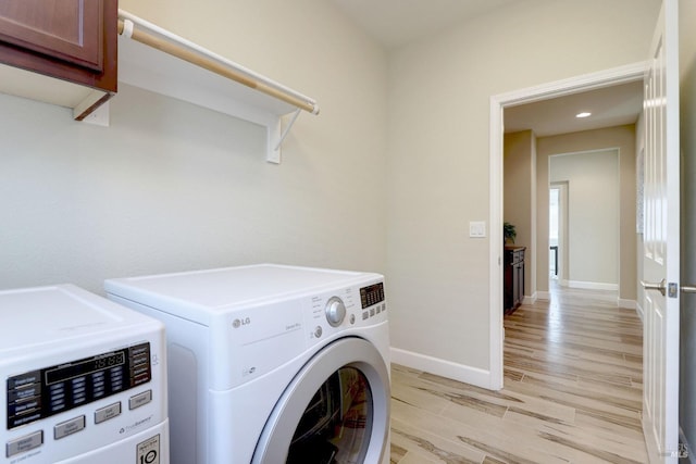 laundry area with separate washer and dryer, light hardwood / wood-style flooring, and cabinets