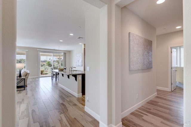 hall featuring light hardwood / wood-style floors and a chandelier