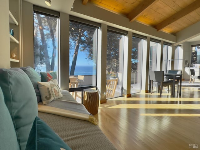 sunroom featuring lofted ceiling with beams, wooden ceiling, a water view, and a wealth of natural light