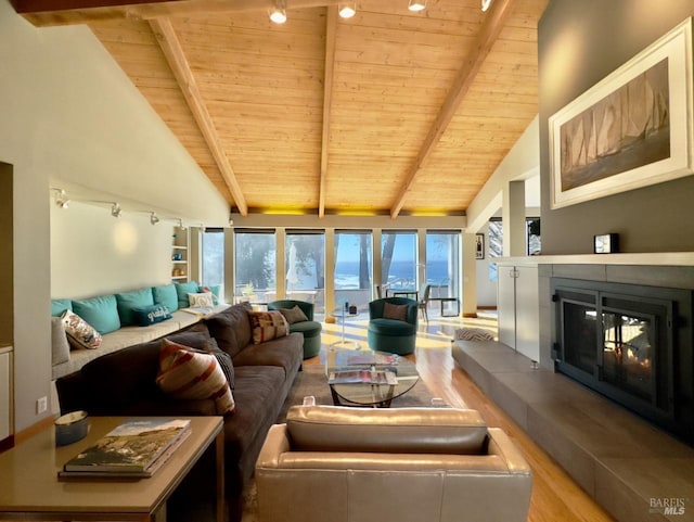 living room with beamed ceiling, a tile fireplace, wooden ceiling, light wood-type flooring, and a water view