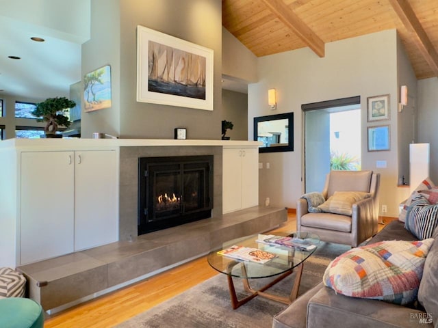 living room with hardwood / wood-style floors, a tiled fireplace, high vaulted ceiling, wooden ceiling, and beamed ceiling