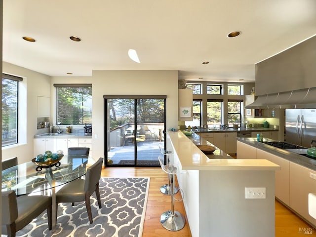 kitchen with sink, stainless steel fridge, kitchen peninsula, and light wood-type flooring