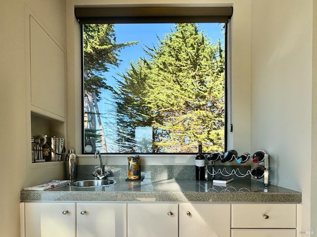 kitchen with white cabinets, light stone countertops, and sink