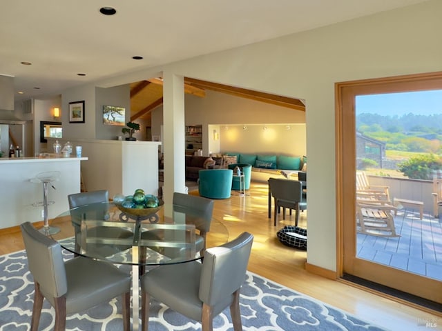 dining space with vaulted ceiling with beams and light wood-type flooring