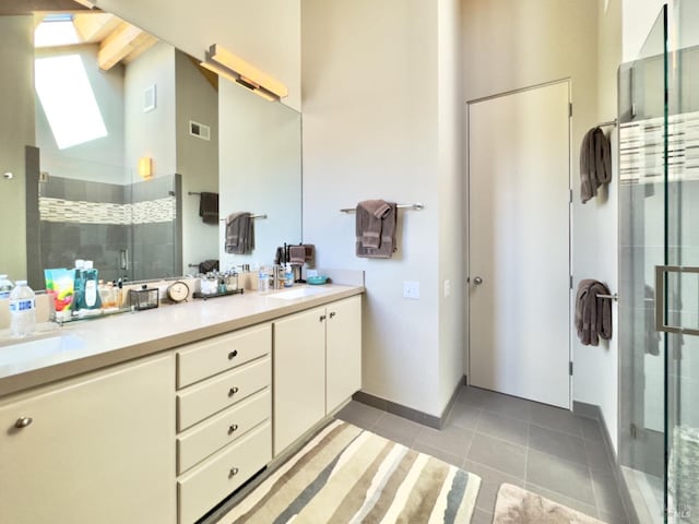 bathroom with a skylight, an enclosed shower, vanity, beam ceiling, and tile patterned flooring