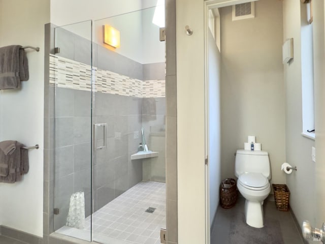 bathroom with a shower with door and toilet