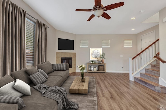 living room featuring hardwood / wood-style floors, a tiled fireplace, ceiling fan, and a wealth of natural light