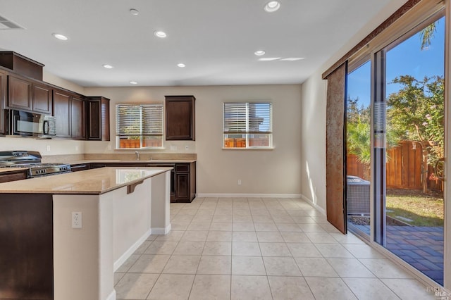 kitchen featuring sink, a healthy amount of sunlight, stainless steel range with gas cooktop, and a center island